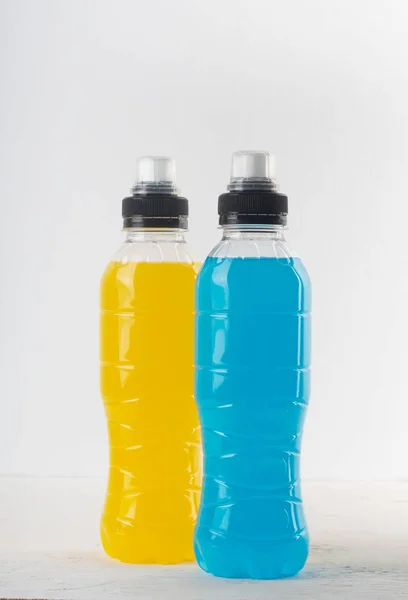 Bebida energética isotónica. Garrafas com líquido transparente azul e amarelo, bebida esportiva em um fundo branco — Fotografia de Stock