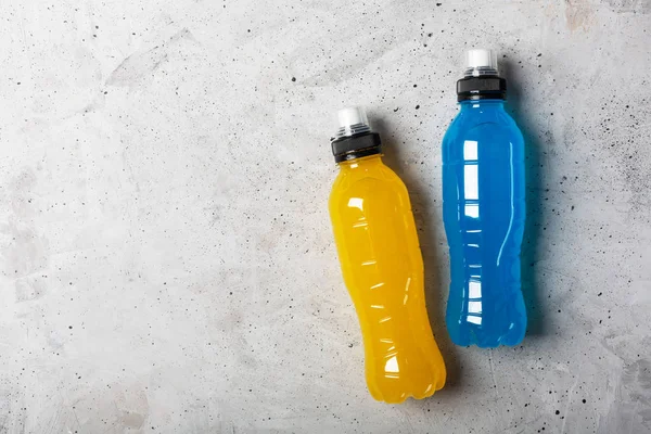 Isotonic energy drink. Bottles with blue and yellow transparent liquid, sport beverage on a gray concrete background — Stock Photo, Image