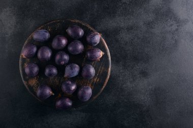 Koyu ahşap arka plan üzerinde bir kase içinde taze incir, kopya alanı ile üst görünümü