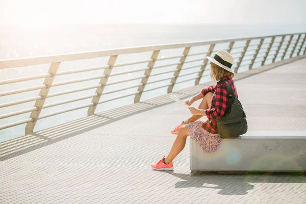 A young woman with a backpack sits on the walk bridge near seaport of Alicante — Stock Photo, Image