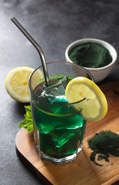 Green drink prepared with single celled green algae chlorella. Detox superfood in the glass. Dark and moody