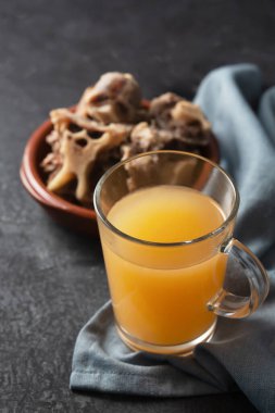 Siyah arka planda cam kavanozda ev yapımı sığır eti çorbası. Kemikler, vücuda proteinlerin yapı taşları olan amino asitleri sağlayan kolajen içerir.