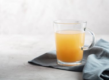 Gri beton arka planda, gözlüklü ev yapımı sığır eti çorbası. Kemikler, vücuda proteinlerin yapı taşları olan amino asitleri sağlayan kolajen içerir.