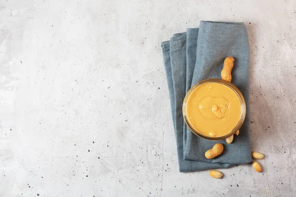 Pindakaas in een glazen pot op tafel, bovenaanzicht — Stockfoto