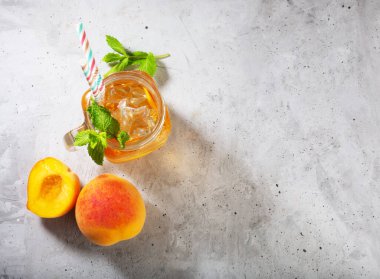 Beton gri zemin üzerinde şeftalili buzlu çay. Nane ve buzlu.