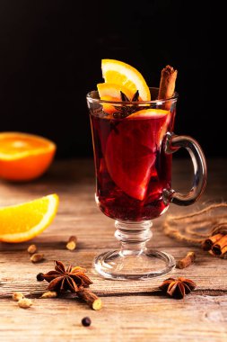 Portakal dilimli sıcak şarap ve anason, kakule ve tarçın gibi baharatlar ahşap arka planda.