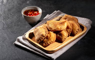 Tipik Kolombiya börekleri genellikle siyah arka planda, yatay ve baharatlı sosla servis edilir.