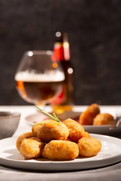 Tapas kroketleri, arka planda bira şişesi olan geleneksel İspanyol ya da Fransız atıştırmalıkları.