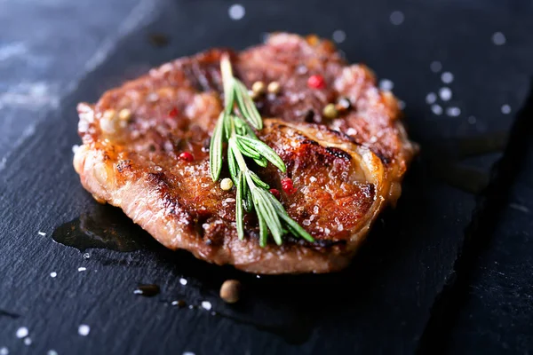 Rindersteak auf dunklem Teller mit Rosmarin und Pfeffer — Stockfoto