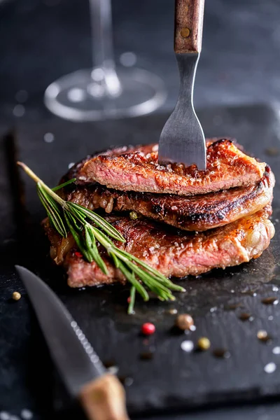 Bistecca di manzo su un piatto scuro con rosmarino e pepe — Foto Stock