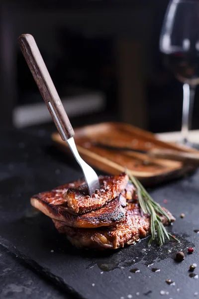 Steak de boeuf sur une assiette sombre avec romarin et poivre — Photo