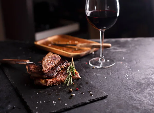 Steak de boeuf sur une assiette sombre avec romarin et poivre — Photo