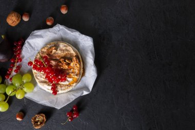 Koyu arkaplanda meyveli, fındıklı ve meyveli Camembert peyniri.
