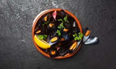 Koyu arkaplanda limonlu haşlanmış midye.