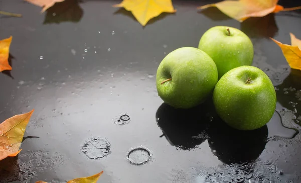 緑のリンゴとオークの葉は雨が降る暗い背景にあります — ストック写真