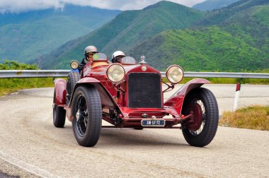 Klasik Alfa Romeo 6C 1750, Mille Miglia 2010 tarihi rallisinde Umbria 'daki dolambaçlı dağ yollarında miğfer takan iki sürücüyle yarışıyor. Umbria, İtalya, 6 Mayıs 2010.