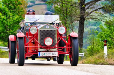 Mille Miglia tarihi yarışına katılan klasik kırmızı Lancia Lambda Tipi 221 Örümcek, Spoleto, İtalya yakınlarındaki manzaralı bir kırsal yolda kask takan iki pilot tarafından kullanılıyor, Mayıs 2010.