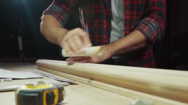 La mano de cerca frota un producto de madera con papel de lija, cámara lenta — Vídeo de stock