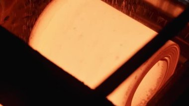 Taşıyıcı üzerinde kırmızı-sıcak metal levha döner. Yavaş hareketler.