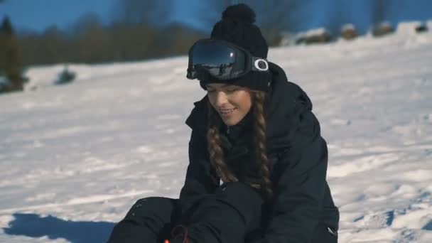 Snowboarder femenino o esquiador sentado en las montañas durante las nevadas — Vídeos de Stock