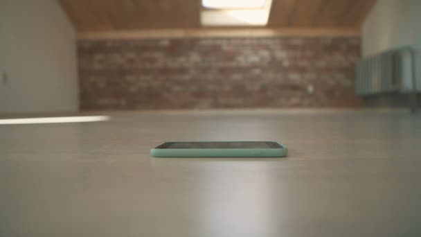 Ragazza fare diversi passi e sedersi sul pavimento per fare clic telefono blu — Video Stock