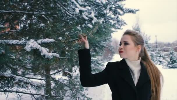 Brunette rijke vrouw in zwarte jas op achtergrond van kerstboom slow motion — Stockvideo