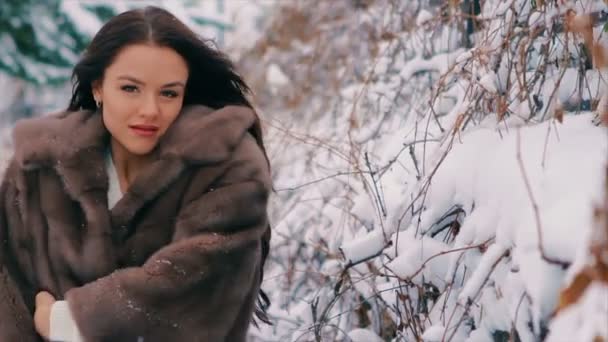 Brunett rik kvinna midja kappa brun päls på bakgrund av träd slowmotion — Stockvideo