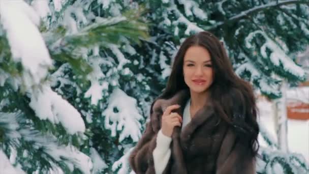 Брюнетка жінка трясти від зимових соснових гілок повільному снігу — стокове відео
