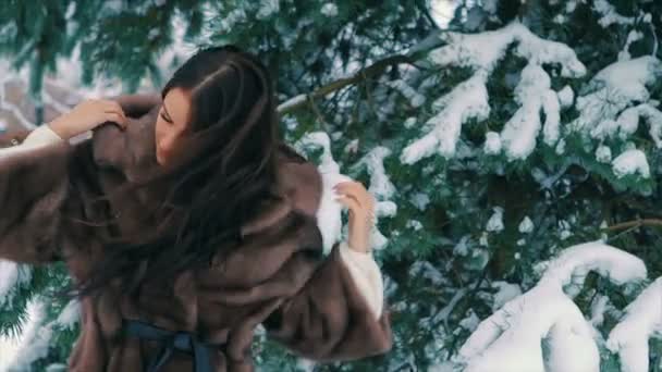 Брюнетка богатая женщина талия пальто из коричневого меха на фоне рождественской елки замедленного движения — стоковое видео