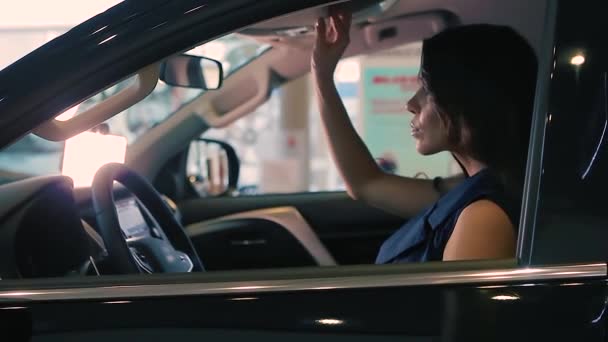 Brunette Woman est assise dans une nouvelle voiture noire. Elle regarde dans le rétroviseur . — Video