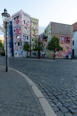 Renkli, komik görünüşlü çarpıcı bir şekilde eğimli bir bina. Canlı şekiller ve desenler evi tuhaf ve hayat dolu gösteriyor..