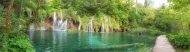 Saf su şelale üzerinde Plitvice Milli Parkı son güneş ışığı yanar. Renkli bahar yeşil orman ile mavi Gölü Panoraması. Harika kırsal görünümü Hırvatistan, Europe.