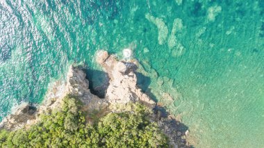 Üstten görünüm hava atış tropikal deniz sahil plaj, kayalar, ağaçlar ve mavi su ile
