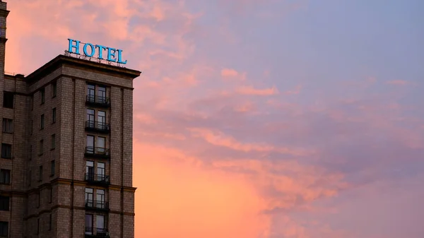 풍화되고 불에 타버린 네온 호텔 사인은 뉴욕의 일몰에 화려하고 극적인 빨간색과 주황색 하늘에 불을 붙였습니다. — 스톡 사진