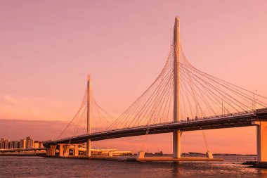 Neva Nehri ağzına gün batımı sırasında altın saat içinde daire Otoban yolu köprüsü. Petersburg şehir binaların ve bitiş körfez manzarasının akşam