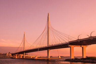 Neva Nehri ağzına gün batımı sırasında altın saat içinde daire Otoban yolu köprüsü. Petersburg şehir binaların ve bitiş körfez manzarasının akşam