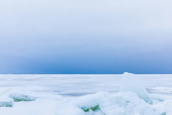 海の冬湾は雪と氷で覆われています 海と海岸に流氷のヒープの曇り空 白い表面と白と青の美しい風景 — ストック写真