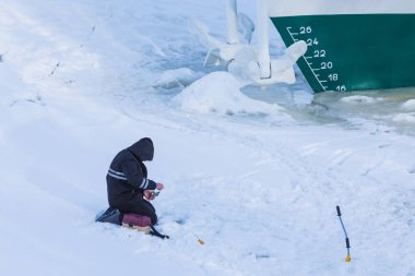 Buz ve kar kış nehir shipwith arka plan üzerinde çapa buz esaret altında oturan yalnız balıkçı 