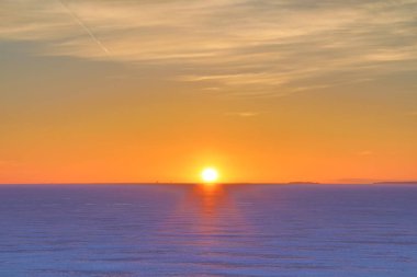 Gündoğumu ve günbatımı. Kırmızı, turuncu, koyu kırmızı, mor, mor ve mavi parlak ve canlı coloures ayarı ile veya yükselen güneş deniz, göl veya bay buz ve kar ile kaplı içinde bulutlu gökyüzü cloured