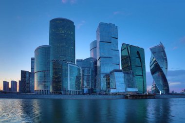 Moskova/ Rusya 19 Nisan 2019: Moskova şehrinin eşsiz gökdeleni, Rusya'nın başkentinin kalbindeki modern ofis merkezi akşam saatlerinde Moskva nehri kıyısında batan güneşin ışınlarıyla