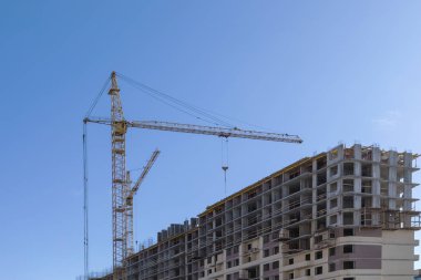 Evin binası. Mavi gökyüzünün arka planda açık güneşli bir günde vinç ve yeni tuğla bina