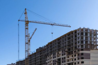 Evin binası. Mavi gökyüzünün arka planda açık güneşli bir günde vinç ve yeni tuğla bina