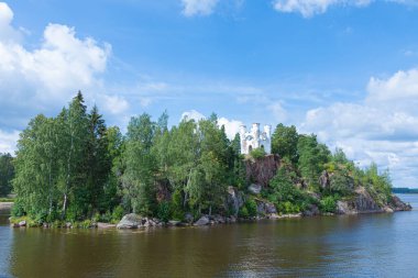 Eski yalnız kale, küçük kale, deniz feneri ya da deniz feneri ya da dağın tepesindeki yeşil kale ile okyanus, deniz, göl suyu arasında açık güneşli yaz günlerinde dalgalar