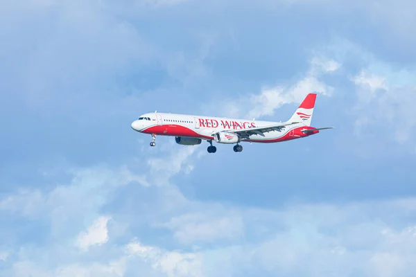 Pulkovo havaalanı Saint Petersburg / Rusya yakınları - 19 Eylül 2020: Yandan iniş yapan veya mavi bulutlu gökyüzünün arka planında havalanan kırmızı kanatlı uçak