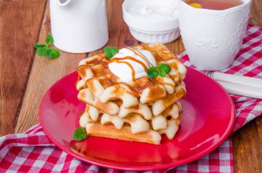 Karamel sos ve bir plaka üzerinde krem şanti ile yığın Belçika Waffle.