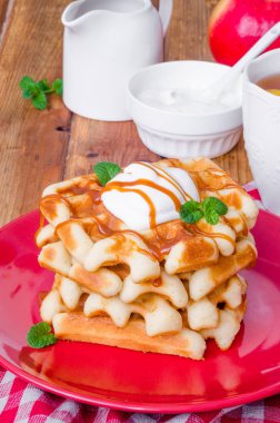 Karamel sos ve bir plaka üzerinde krem şanti ile yığın Belçika Waffle.