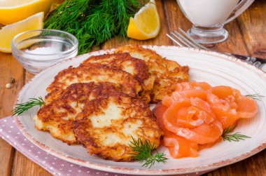 Ekşi krema ve somon ahşap arka plan üzerinde bir plaka üzerinde patates pancakes