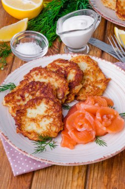 Ekşi krema ve somon ahşap arka plan üzerinde bir plaka üzerinde patates pancakes