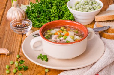 Yeşil bezelye ve sebze ahşap arka plan üzerinde bir kase ile tavuk çorbası