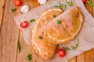 Pizza Calzone domates sosu, peynir, otlar, mantar ve sosis